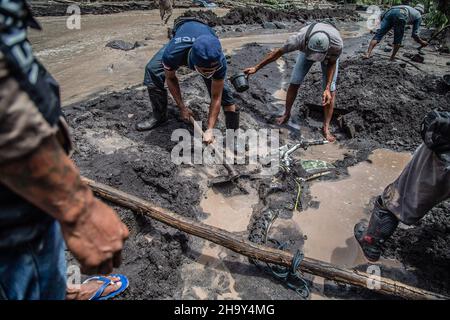 Kamar Kajang, Indonesien. 09th Dez 2021. Dorfbewohner versuchen, ein Motorrad zu entfernen, das nach dem Ausbruch des Berges Semeru in Kamar Kajang, Lumajang, von der kalten Lava begraben wurde. Mindestens 14 Menschen sind tot und Dutzende werden verletzt, nachdem Mount Semeru, ein Vulkan in der indonesischen Provinz Ost-Java, am Samstag ausbrach und Aschetürme und heiße Wolken warf, die nahe gelegene Dörfer bedeckten. Kredit: SOPA Images Limited/Alamy Live Nachrichten Stockfoto