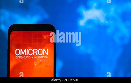 Omicron-Variante des Coronavirus. Mobiltelefon mit omicron-Text vor dem Hintergrund der Weltkarte. SARS-CoV-2, B.1.1.529. Welt-Epidemie-Konzept, Nahaufnahme Stockfoto