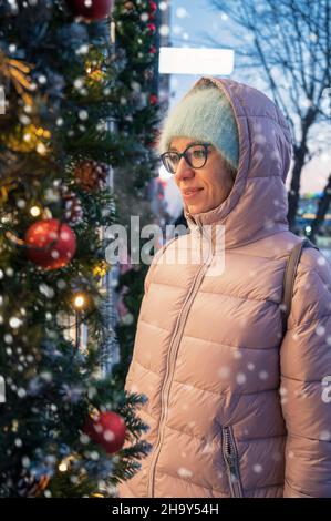 Hübsche Frau in der Nähe beleuchteten Neujahr dekoriert Fenster. Weihnachtsferien oder Shopping auf Neujahr oder Weihnachten Konzept Stockfoto