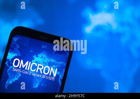 Omicron-Variante des Coronavirus. Mobiltelefon mit omicron-Text vor dem Hintergrund der Weltkarte. SARS-CoV-2, B.1.1.529. Konzept der Weltepidemie Stockfoto