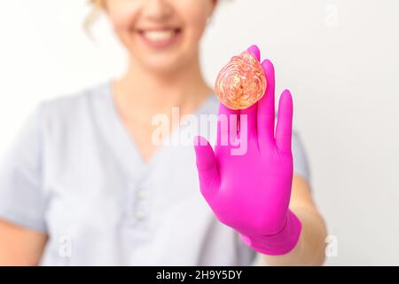 Gelbe Zuckerpaste in der Hand Meister der Enthaarung. Lächelnde Kosmetikerin hält Wachs zur Enthaarung auf weißem Hintergrund. Konzept der Epilation Stockfoto