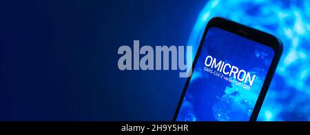 Omicron-Variante des Coronavirus. Banner, Mobiltelefon mit omicron-Text auf der globalen Karte des Planeten Erde. SARS-CoV-2, B.1.1.529. Weltepidem Stockfoto