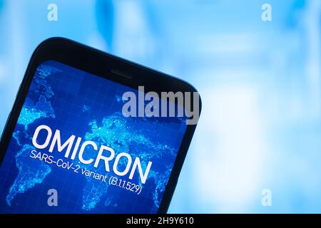 Omicron-Variante des Coronavirus. Mobiltelefon mit omicron-Text vor Krankenhaushintergrund. SARS-CoV-2, B.1.1.529. Konzept der Weltepidemie Stockfoto
