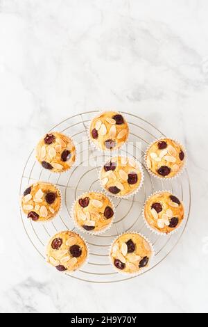 Hausgemachte Kirschmuffins auf einem Kühlregal auf weißem Marmorboden mit Platz für Kopien. Draufsicht. Stockfoto