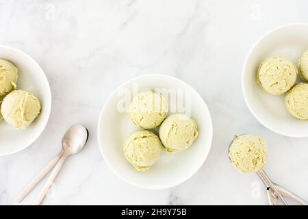 Kugeln hausgemachtes Avocado-Eis in weißen Schalen und auf Eis Kugel über weißen Marmor mit Kopierfläche. Draufsicht. Stockfoto