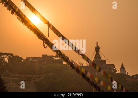 Trübes goldenes Morgenlicht auf dem Swayambhunath-Tempelkomplex und Gebetsfahnen in Kathmandu, Nepal. Stockfoto