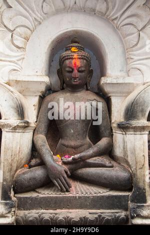 Eine geschnitzte Steinstatue von Buddha, die in einer Lotusposition im Swayambhunath-Tempelkomplex in Kathmandu, Nepal, sitzt. Stockfoto