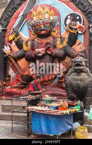 Ein Händler verkauft Opfergaben am Hindu-Schrein des Kala oder Black Bhairab auf dem Durbar Square, Kathamandu, Nepal. Der Schwarze Bhairab ist der zerstörerische Stockfoto