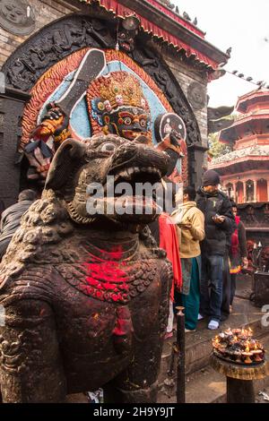 Ein steinerner Tempellöwe bewacht den Hindu-Schrein des Kala oder Black Bhairab auf dem Durbar Square, Kathamandu, Nepal. Der Schwarze Bhairab ist der destruktive in Stockfoto