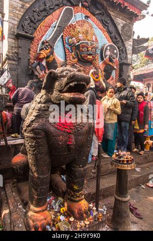 Ein steinerner Tempellöwe bewacht den Hindu-Schrein des Kala oder Black Bhairab auf dem Durbar Square, Kathamandu, Nepal. Der Schwarze Bhairab ist der destruktive in Stockfoto