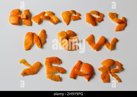 Unschärfe-Effekt Neujahrs-Wort, dargestellt durch orange trockene Schale auf grauem Hintergrund. Dekoration für Silvester, Konzept. Grußkarte. Text und DIY-Briefe. Stockfoto