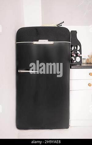 Kleiner schwarzer Retro Kühlschrank in weißer Küche, schwarzer Kühlschrank im Vintage-Stil auf weißem Hintergrund. Nahaufnahme. Hochwertige Fotos Stockfoto