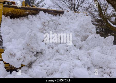 Der gelbe Traktor reinigt die Straße im Schnee Stockfoto