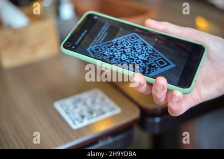 Nahaufnahme der Gäste, die eine Mahlzeit im Restaurant bestellen, während der QR-Code mit dem Mobiltelefon gescannt wird, um ein Online-Menü zu erhalten. Stockfoto