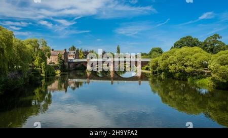 Blauer Sommerhimmel, der sich auf den Fluss Nith in Dumfries spiegelt, mit der Brücke von A780 im Hintergrund Stockfoto