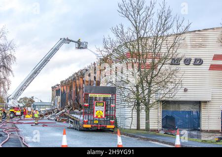 Kidderminster, Großbritannien, 8th. Dezember 2021. Feuerwehrleute und Polizei sind immer noch beim Lagerfeuer auf dem Hoo Farm Industrial Estate, Kidderminster. Die Überreste des Gebäudes von MCD werden noch 48 Stunden nach Beginn des Feuers mit Wasser übergossen. Rauch und kleine Brände sind immer noch offensichtlich, da die Feuerwehr nun die Kontrolle über die Situation hat. Kredit: Lee Hudson Stockfoto