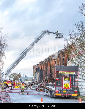 Kidderminster, Großbritannien, 8th. Dezember 2021. Feuerwehrleute und Polizei sind immer noch beim Lagerfeuer auf dem Hoo Farm Industrial Estate, Kidderminster. Die Überreste des Gebäudes von MCD werden noch 48 Stunden nach Beginn des Feuers mit Wasser übergossen. Rauch und kleine Brände sind immer noch offensichtlich, da die Feuerwehr nun die Kontrolle über die Situation hat. Kredit: Lee Hudson Stockfoto