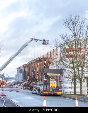 Kidderminster, Großbritannien, 8th. Dezember 2021. Feuerwehrleute und Polizei sind immer noch beim Lagerfeuer auf dem Hoo Farm Industrial Estate, Kidderminster. Die Überreste des Gebäudes von MCD werden noch 48 Stunden nach Beginn des Feuers mit Wasser übergossen. Rauch und kleine Brände sind immer noch offensichtlich, da die Feuerwehr nun die Kontrolle über die Situation hat. Kredit: Lee Hudson Stockfoto