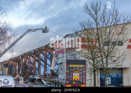 Kidderminster, Großbritannien, 8th. Dezember 2021. Feuerwehrleute und Polizei sind immer noch beim Lagerfeuer auf dem Hoo Farm Industrial Estate, Kidderminster. Die Überreste des Gebäudes von MCD werden noch 48 Stunden nach Beginn des Feuers mit Wasser übergossen. Rauch und kleine Brände sind immer noch offensichtlich, da die Feuerwehr nun die Kontrolle über die Situation hat. Kredit: Lee Hudson Stockfoto