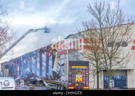 Kidderminster, Großbritannien, 8th. Dezember 2021. Feuerwehrleute und Polizei sind immer noch beim Lagerfeuer auf dem Hoo Farm Industrial Estate, Kidderminster. Die Überreste des Gebäudes von MCD werden noch 48 Stunden nach Beginn des Feuers mit Wasser übergossen. Rauch und kleine Brände sind immer noch offensichtlich, da die Feuerwehr nun die Kontrolle über die Situation hat. Kredit: Lee Hudson Stockfoto