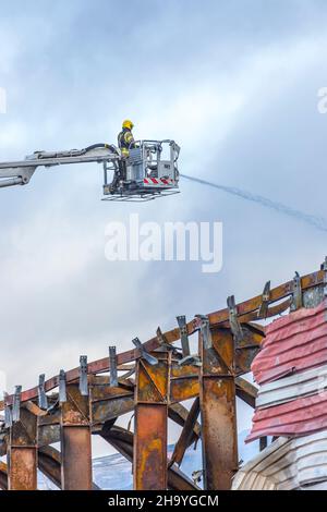 Kidderminster, Großbritannien, 8th. Dezember 2021. Feuerwehrleute und Polizei sind immer noch beim Lagerfeuer auf dem Hoo Farm Industrial Estate, Kidderminster. Die Überreste des Gebäudes von MCD werden noch 48 Stunden nach Beginn des Feuers mit Wasser übergossen. Rauch und kleine Brände sind immer noch offensichtlich, da die Feuerwehr nun die Kontrolle über die Situation hat. Kredit: Lee Hudson Stockfoto