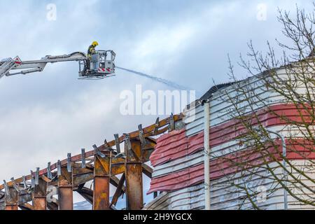 Kidderminster, Großbritannien, 8th. Dezember 2021. Feuerwehrleute und Polizei sind immer noch beim Lagerfeuer auf dem Hoo Farm Industrial Estate, Kidderminster. Die Überreste des Gebäudes von MCD werden noch 48 Stunden nach Beginn des Feuers mit Wasser übergossen. Rauch und kleine Brände sind immer noch offensichtlich, da die Feuerwehr nun die Kontrolle über die Situation hat. Kredit: Lee Hudson Stockfoto