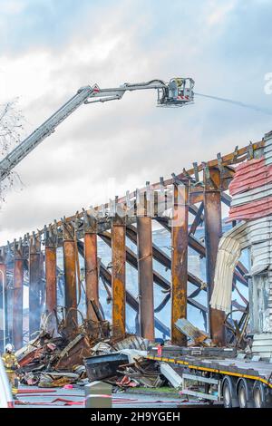 Kidderminster, Großbritannien, 8th. Dezember 2021. Feuerwehrleute und Polizei sind immer noch beim Lagerfeuer auf dem Hoo Farm Industrial Estate, Kidderminster. Die Überreste des Gebäudes von MCD werden noch 48 Stunden nach Beginn des Feuers mit Wasser übergossen. Rauch und kleine Brände sind immer noch offensichtlich, da die Feuerwehr nun die Kontrolle über die Situation hat. Kredit: Lee Hudson Stockfoto