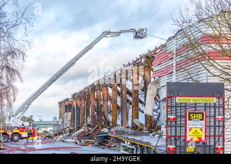 Kidderminster, Großbritannien, 8th. Dezember 2021. Feuerwehrleute und Polizei sind immer noch beim Lagerfeuer auf dem Hoo Farm Industrial Estate, Kidderminster. Die Überreste des Gebäudes von MCD werden noch 48 Stunden nach Beginn des Feuers mit Wasser übergossen. Rauch und kleine Brände sind immer noch offensichtlich, da die Feuerwehr nun die Kontrolle über die Situation hat. Kredit: Lee Hudson Stockfoto