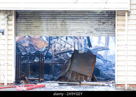 Kidderminster, Großbritannien, 8th. Dezember 2021. Feuerwehrleute und Polizei sind immer noch beim Lagerfeuer auf dem Hoo Farm Industrial Estate, Kidderminster. Die Überreste des Gebäudes von MCD werden noch 48 Stunden nach Beginn des Feuers mit Wasser übergossen. Rauch und kleine Brände sind immer noch offensichtlich, da die Feuerwehr nun die Kontrolle über die Situation hat. Kredit: Lee Hudson Stockfoto