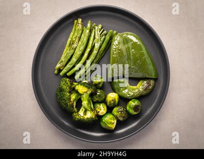 Heißer Ofen geröstetes grünes Gemüse auf dunkler Keramikplatte. Gesundes Lebensmittelkonzept Stockfoto