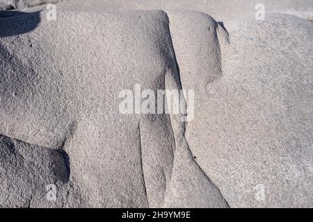 Granitgraue Gesteinsformation, die durch die Meersalz- und Windstruktur erodiert wird. Glatte mineralgealterte rissige Oberfläche auf Kolymbithres Paros Insel Gree Stockfoto