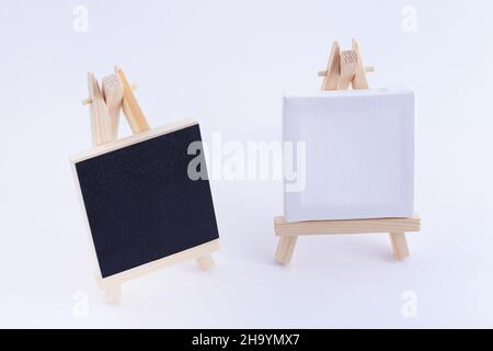 Zwei hölzerne Easels Miniatur mit blanker schwarzer und weißer quadratischer Leinwand für Künstler und Maler - Mockup. Mini-Holzständer mit sauberer Zeichenfläche auf weißem Hintergrund, Copy Space Stockfoto