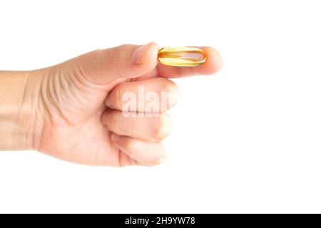 Hand hält eine durchsichtige Fischölpille isoliert auf weißem Hintergrund. Stockfoto