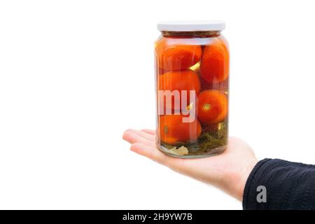 Männliche Hand hält ein Glas eingelegter Tomaten mit Pflaumen vor einem weißen Hintergrund Stockfoto