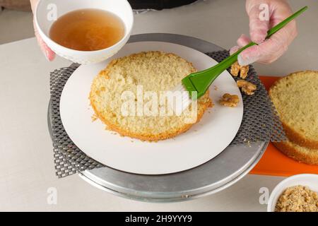 Konditor Den Kuchenteig mit Soda befeuchten, bevor die Füllung hinzugefügt wird. Stockfoto