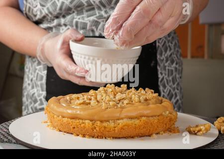 Konditor setzt Walnüsse in die brigadeiro-Füllung (Seitenansicht). Stockfoto