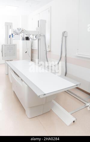 Röntgenabteilung im modernen Krankenhaus. Röntgenraum mit Scangerät und leerem Bett. Techniker, der ein Röntgengerät anpasst. Scannen von Brust, Herz Stockfoto