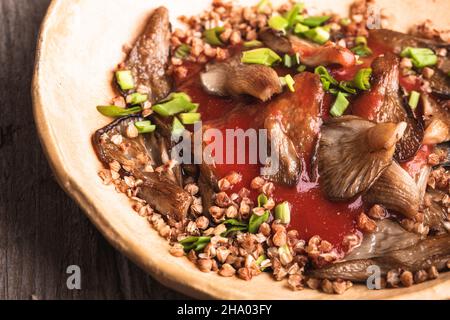 Gesundes veganes Essen, auf Goumet-Pflanzen basierendes Gericht. Austernpilze und Buchweizen in Pfeffertomatensoße Stockfoto