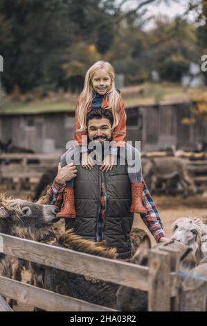 Bauer hält seine Tochter auf den Schultern und fühlt sich gut Stockfoto
