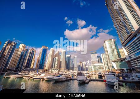 Wunderschöne Aussicht auf die teuren Yachten und Motorboote, die an den Piers der Dubai Marina festgemacht sind, umgeben von hohen Wolkenkratzern, Dubai, VAE Stockfoto