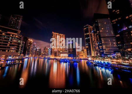 Szenische Langzeitaufnahme der Dubai Marina mit ihren hohen Wolkenkratzern, die sich neben den Jachthäfen und der Uferpromenade, Dubai, VAE, erheben Stockfoto