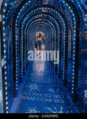 In einem Lichttunnel in Covent Garden, London, wo sich eine Person unter einem Regenschirm befindet, wurde sie blau, um Frozen zu fördern. Stockfoto
