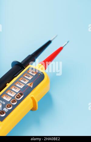 Gelbe Spannungsanzeige auf blauem Hintergrund. Freiraumprüfung und Verifizierung von elektrischen Netzen Stockfoto