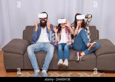 Glad Familie tragen vr Gläser sitzen auf dem Sofa zu Hause, zukünftige Technologie Stockfoto