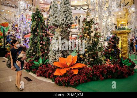 Kuala Lumpur, Malaysia. 09th Dez 2021. Ein Shopper mit einem Baby sah eine Gesichtsmaske als Vorsichtsmaßnahme gegen die Ausbreitung von Covid-19, als sie an den Weihnachtsdekorationen in einem Einkaufszentrum in Kuala Lumpur vorbeiging. (Foto von Wong Fok Loy/SOPA Images/Sipa USA) Quelle: SIPA USA/Alamy Live News Stockfoto