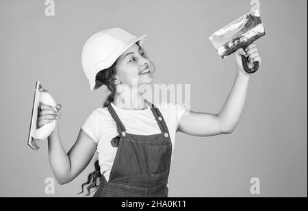 Fröhliche Kinderarbeiter mit Gebäude Uniform und Putzspachtel, Ausrüstung Stockfoto