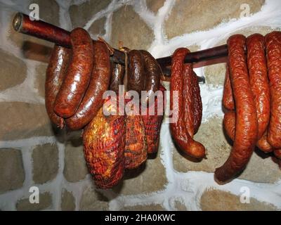 Traditionelle hausgemachte Räucherwürste und Schinken hängen in der Speisekammer, Produkt aus Polen Stockfoto