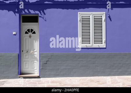 Die Eingangstür aus weißem Holz und das weiße Fenster an einer sehr peri Wand mit grauen Ziegelsteinen. Stockfoto