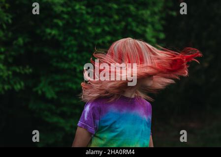 Junges Mädchen schüttelt die Haare draußen mit gefärbten roten Haaren Stockfoto