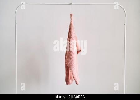 Ein Wollpullover, der auf einem Kleiderbügel auf weißem Hintergrund hängt. Warme Kleidung im Sonderangebot. Stockfoto